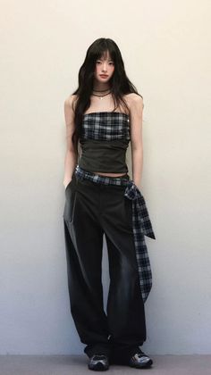 Woman with long dark hair wearing a plaid tube top and wide leg pants