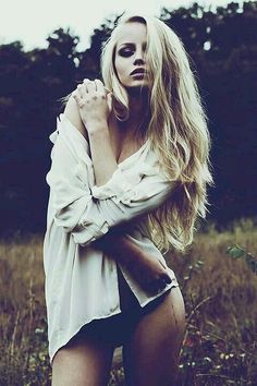Woman with long blonde hair in an unbuttoned white shirt outdoors