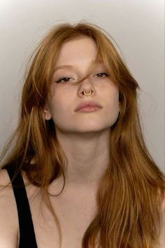 Woman with long red hair and a septum ring wearing a black top