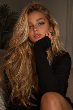 Woman with long blonde hair and blue eyes in a black top, looking at the camera