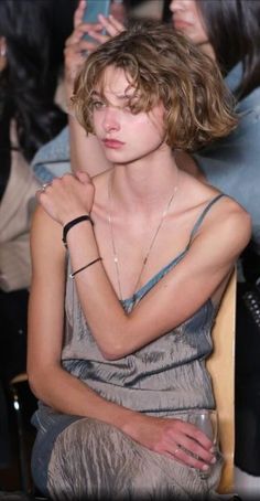 Woman with short curly hair wearing a spaghetti strap top indoors