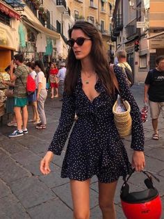 Woman in a polka dot dress and sunglasses walking on a busy street
