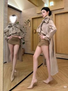 Woman in a long coat and mini skirt posing in front of a mirror