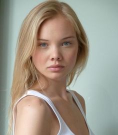 Woman with blonde hair and blue eyes wearing a white tank top