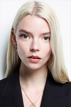 Woman with long blonde hair wearing a black blazer and gold jewelry