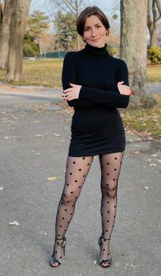 Woman in a black dress and polka dot tights posing outdoors