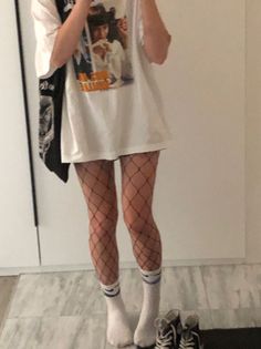 Person in an oversized t-shirt and fishnet stockings taking a mirror selfie