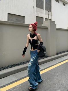 Woman with red hair in a crop top and ripped jeans walking on a street