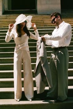 Couple on stairs, woman in wide leg pants and sun hat, man in shirt and trousers