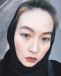 Woman with blue eyes wearing a black hijab in a close-up outdoor shot