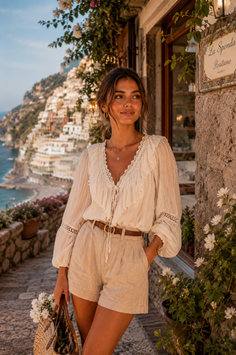 Woman in a white blouse and linen shorts in a coastal town at golden hour