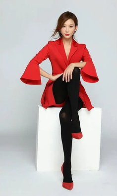 Woman in a red blazer and black tights posing in a studio