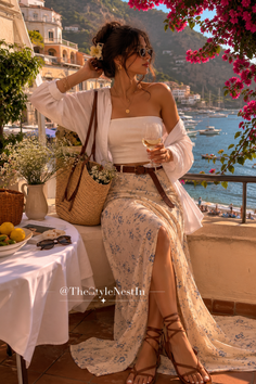 Woman in a long skirt and strapless top on a balcony overlooking a coastline