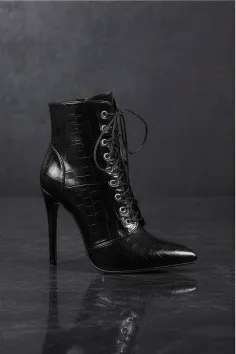 Black high-heeled lace-up ankle boot with crocodile texture on a dark background
