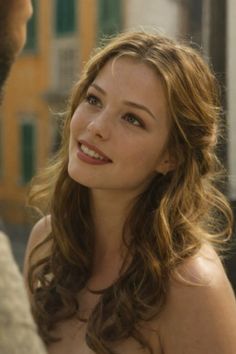Woman with long wavy hair and freckles smiling outdoors