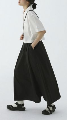 Person in a white short-sleeve shirt and black wide-leg pants with sandals