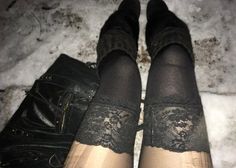 Person wearing black lace-trimmed stockings and boots in the snow