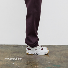 Person wearing white sneakers and burgundy pants on a concrete floor