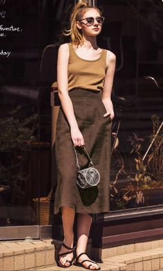 Woman in a tank top and midi skirt with sunglasses and a ponytail outdoors