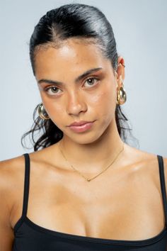 Woman with dark hair and gold jewelry in a studio portrait