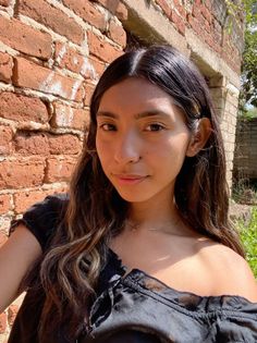Woman with long hair wearing an off-shoulder black top outdoors