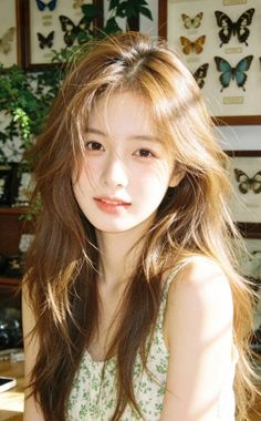 Woman with long brown hair in a green floral top, bathed in soft indoor light