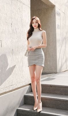 Woman in a sleeveless turtleneck and plaid skirt posing on outdoor steps