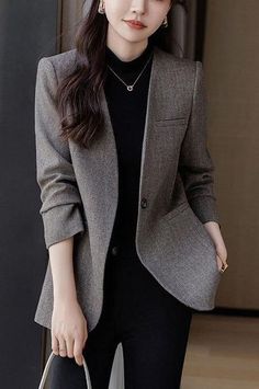Woman in a gray blazer and black turtleneck with long dark hair