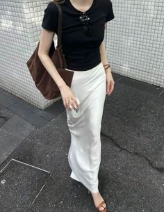 Person in a black t-shirt and white skirt walking on a street