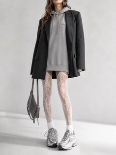 Woman in an oversized blazer, hoodie dress, and lace stockings