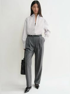 Woman in a striped shirt and grey trousers with a black handbag