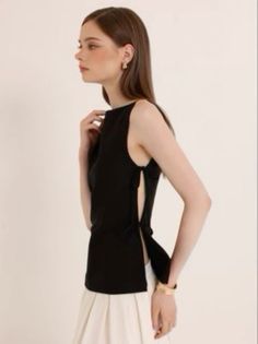 Woman in a black top and white skirt posing in a studio