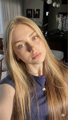 Young woman with blonde hair and freckles wearing a dark t-shirt and gold necklaces