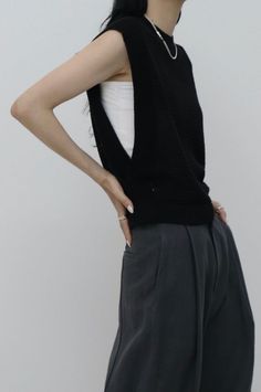 Woman in a black sleeveless top and gray pants with hands on hips