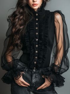 Woman in a black ruffled blouse with sheer sleeves and dark jeans