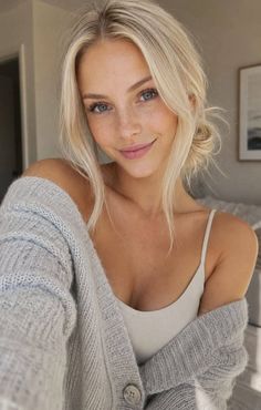 Blonde woman with blue eyes and freckles wearing a cardigan and tank top
