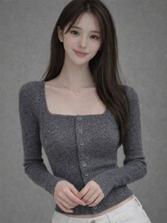 Woman with long hair wearing a gray cardigan and white pants