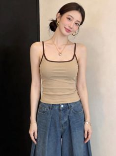 Woman with hair in a bun wearing a beige spaghetti strap top and wide leg jeans
