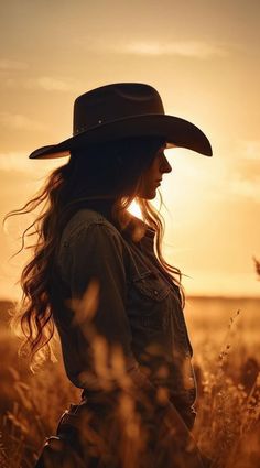 Woman in a cowboy hat and denim jacket in a field at golden hour