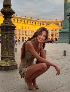 Woman in a mini dress and high heels squatting outdoors at golden hour