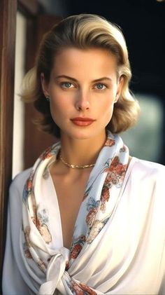 Woman with blonde hair and blue eyes wearing a white blouse and patterned scarf