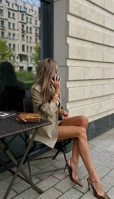 Woman in a blazer and high heels talking on the phone at an outdoor cafe