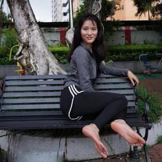 Woman in athletic wear sitting barefoot on a park bench