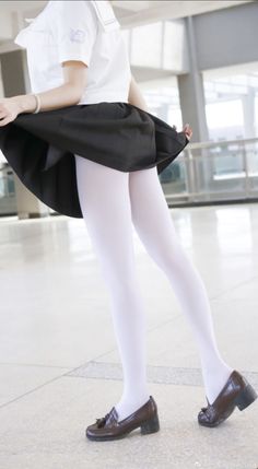 Person in a school uniform with white tights and brown shoes indoors