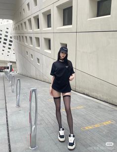 Woman in a black t-shirt and thigh high stockings in an urban setting