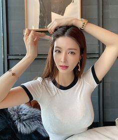 Woman in a white t-shirt with hands on her head, looking at the camera