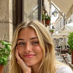 Blonde woman with blue eyes smiling outdoors on a street