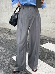 Person in wide leg pants and a blue shirt holding a black handbag