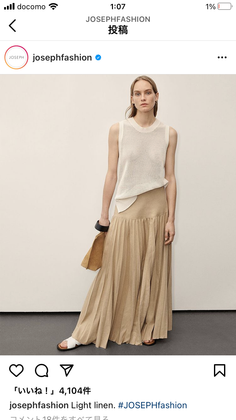 Woman in a sleeveless top and pleated long skirt posing in a studio