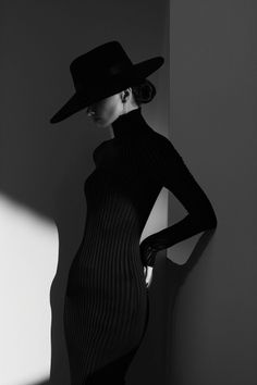 Woman in a black hat and turtleneck dress in dramatic lighting